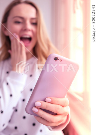 Blonde young girl taking selfie. Video call. Online education. Work from home. Woman holding smartphone. Phone call. Recording new vlog for her channel. Blogger surprised 80022541