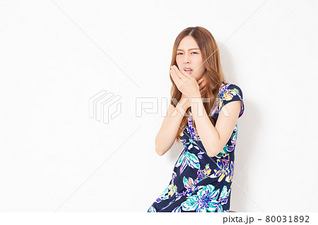 白い壁の前で、喉が痛いジェスチャーをする、青いワンピースを着た若い女性 白い壁の前で、喉が痛いジェスチャーをする、青いワンピースを着た若い女性 80031892