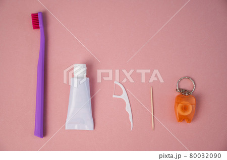 Personal oral hygiene product on a pink background. Toothbrush tube toothpaste toothpick and floss. Flat lay 80032090