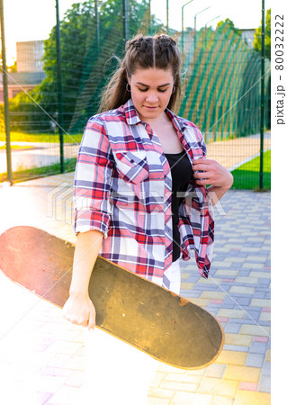 Cute millennial woman smile happy walking down the street with her skateboard. sun backlight and freedom rebel independent concept. Spending day for active board hobby Cute millennial woman smile happy walking down the street with her skateboard. sun backlight and freedom rebel independent concept. Spending day for active board hobby 80032222