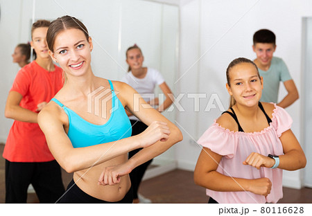 Female instructor fulfilling dance movements with teenagers 80116628