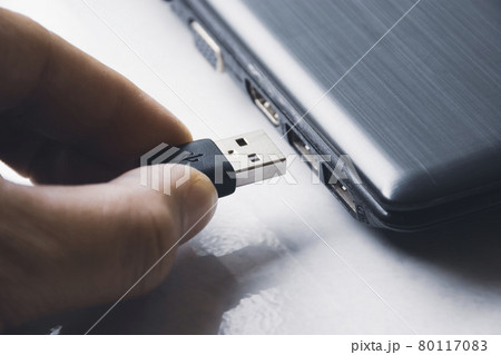 Hand inserting USB (Universal Serial Bus) Type A version 3.0 connecting to usb port of laptop 80117083
