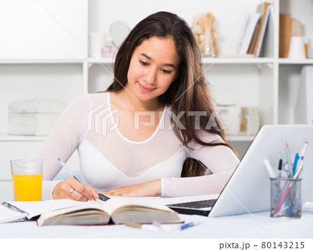 Portrait of young female sitting and writing Portrait of young female sitting and writing 80143215