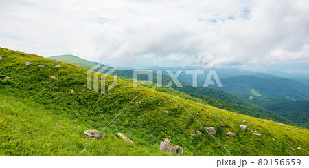 summer mountain landscape. beautiful nature scenery. stones on the grassy hills rolling in to the distant ridge beneath a cloudy sky. travel back country concept 80156659