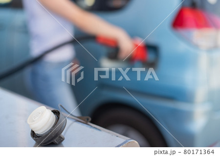 Caucasian woman refueling a car at a self-service gas station. 80171364