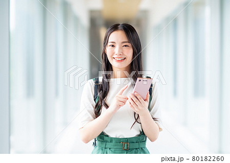 スマホを見る大学生の女の子の写真素材