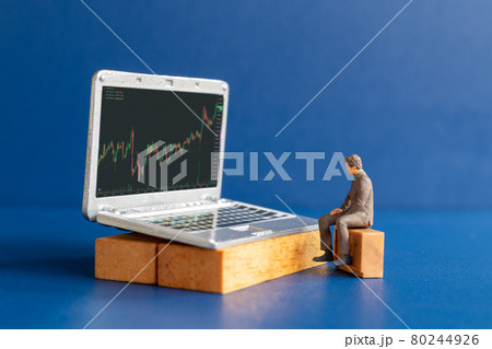 Miniature people, Business people and laptop featuring stock tickers 80244926