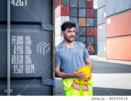 Professional engineer container cargo foreman in helmets is standing and looking area of work for safety and checking stock into the container for loading.logistic and business export.. Professional engineer container cargo foreman in helmets is standing and looking area of work for safety and checking stock into the container for loading.logistic and business export.. 80245619