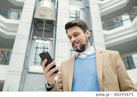 Businessman reading a message on the phone Businessman reading a message on the phone 80245675