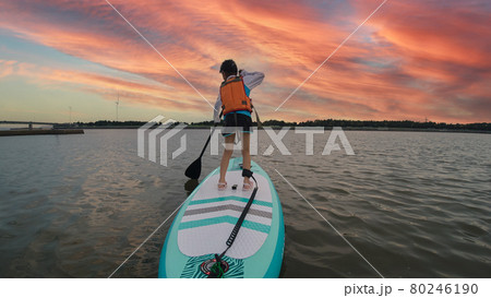 夏の海でサップボードを遊んでいる可愛い子供の様子と綺麗な夕焼けの風景 80246190