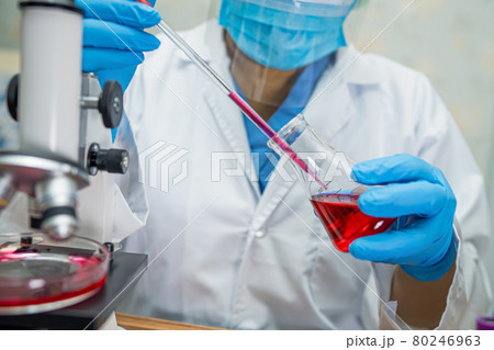 Asian scientist biochemist or microbiologist working research with a microscope in laboratory. For protect outbreak Coronavirus Covid19, bacteria and germs. 80246963