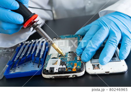 Technician repairing inside of mobile phone by soldering iron. Integrated Circuit. the concept of data, hardware, technology. Technician repairing inside of mobile phone by soldering iron. Integrated Circuit. the concept of data, hardware, technology. 80246965