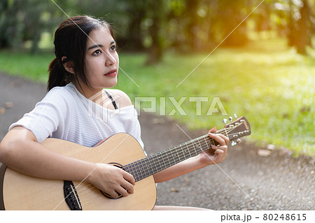 beautiful girl playing guitar at the garden 80248615