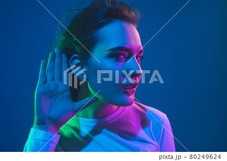Caucasian woman's portrait isolated on blue studio background in pink-green neon light, stylish and beautiful 80249624
