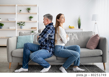 Middle aged married couple sitting back to back on couch, not talking to each other after conflict at home Middle aged married couple sitting back to back on couch, not talking to each other after conflict at home 80251749