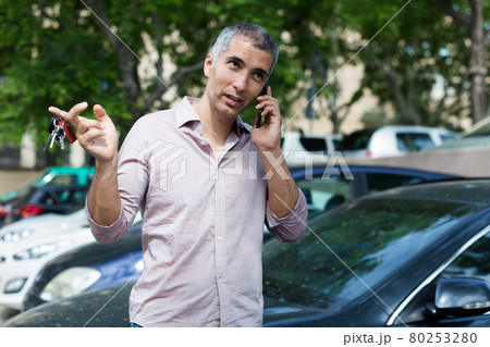 Portrait of man who is standing near his car and talking by phone Portrait of man who is standing near his car and talking by phone 80253280