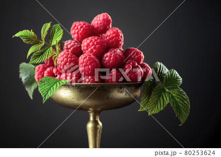 Fresh raspberries with leaves in an old brass dish. 80253624