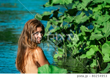 young woman bathes in the river among the leaves of aquatic plants 80254953