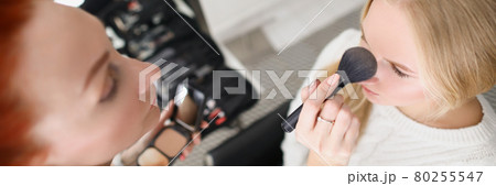 Woman in salon applies powder to blonde with brush Woman in salon applies powder to blonde with brush 80255547