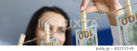 Woman looking at us cash dollars hanging on a rope Woman looking at us cash dollars hanging on a rope 80255549