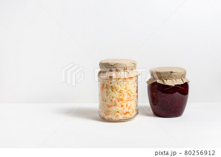 Homemade sauerkraut with carrots and cabbage salad with beets in a glass jar on a white wooden background. Fermented food. Homemade sauerkraut with carrots and cabbage salad with beets in a glass jar on a white wooden background. Fermented food. 80256912