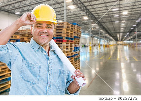 Hispanic Male Contractor Wearing Hard Hat Standing in Empty Industrial Warehouse. Hispanic Male Contractor Wearing Hard Hat Standing in Empty Industrial Warehouse. 80257275