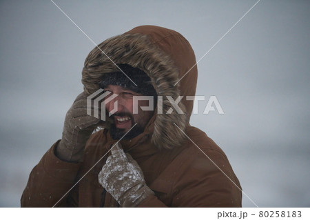 man at winter in stormy weather wearing warm fur jacket 80258183