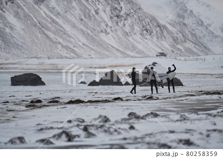 Arctic surfers going by beach after surfing Arctic surfers going by beach after surfing 80258359