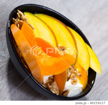 Breakfast with pumpkin and mango served with whipped topping and oat flakes 80259227