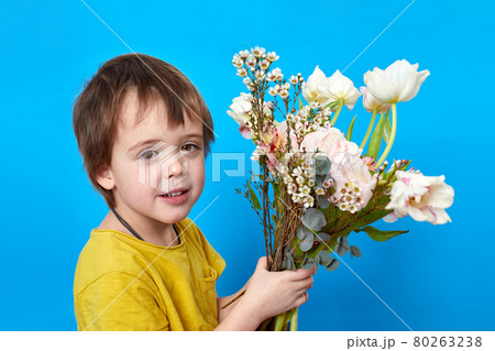 Charming boy with bright blossoming flowers on blue background Charming boy with bright blossoming flowers on blue background 80263238
