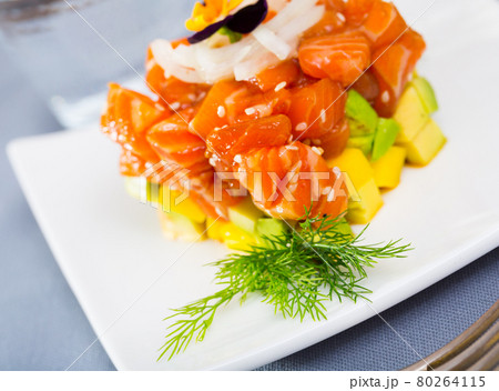 Cube of tasty tartar from red fish and avocado served on plate 80264115