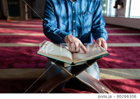 muslim man praying Allah alone inside the mosque and reading islamic holly book 80266306