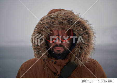 man at winter in stormy weather wearing warm fur jacket 80267681