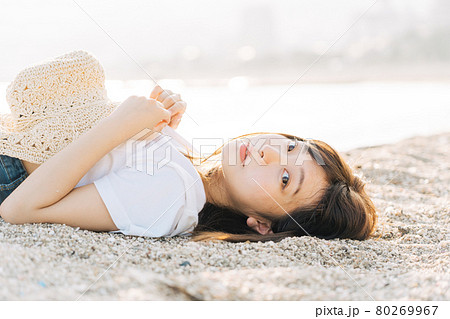 砂浜に寝転がる若い女性 の写真素材