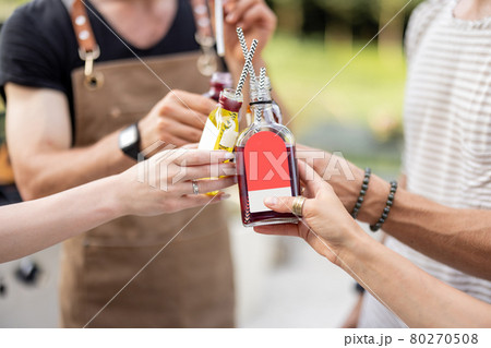 People clinking bottles with a strong alcohol drinks outdoors 80270508