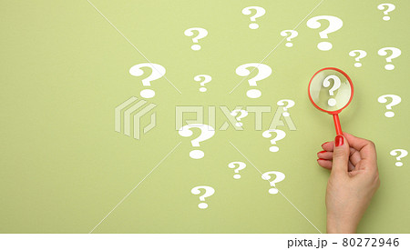 female hand holds a plastic magnifying glass and question marks on a green background. The concept of finding an answer to questions female hand holds a plastic magnifying glass and question marks on a green background. The concept of finding an answer to questions 80272946