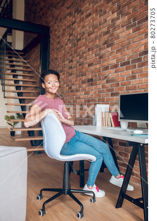 Young african american woman sitting at the table at her working place Young african american woman sitting at the table at her working place 80273705