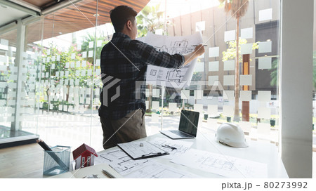 an architect looking the whole schematic blueprint revising the details of the structure 80273992