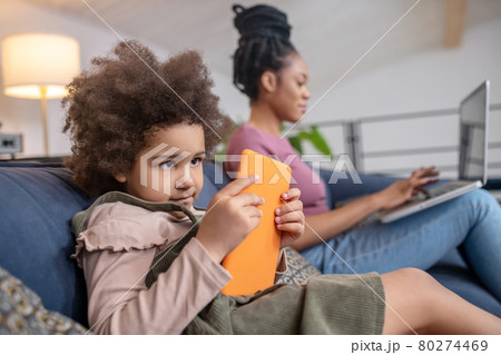 Little girl looking at tablet and woman with laptop Little girl looking at tablet and woman with laptop 80274469
