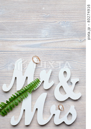 White letters mr and vhk on a wooden background with a ring and a green branch. Top view. Copy place. White letters mr and vhk on a wooden background with a ring and a green branch. Top view. Copy place. 80274916