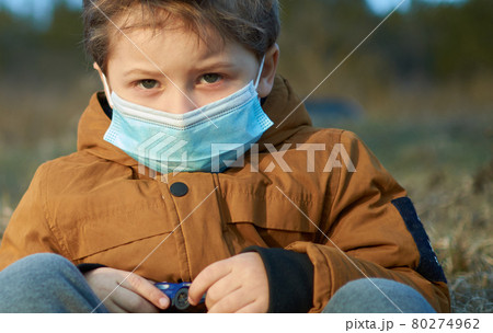 Little boy with protective mask looking in camera outdoor walk in forest 80274962