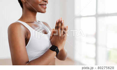 Black female meditating keeping hands together in prayer pose Black female meditating keeping hands together in prayer pose 80275620
