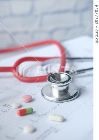 prescription medical pills and a stethoscope on a cardio diagram. 80277054
