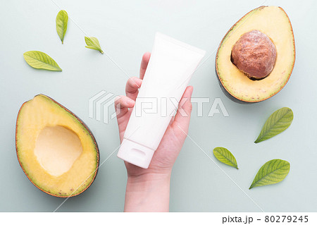 Natural avocado skincare products for healthy skin and hair. Woman hand holding blank white squeeze tube with fresh organic avocado on green background. Beauty herbal skincare and haircare concept. Natural avocado skincare products for healthy skin and hair. Woman hand holding blank white squeeze tube with fresh organic avocado on green background. Beauty herbal skincare and haircare concept. 80279245