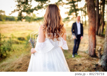 Couple of bride and groom prepared for the wedding, in a beautiful field facing Couple of bride and groom prepared for the wedding, in a beautiful field facing 80279759