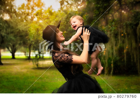 Hand in black dress plays with her daughter in black dress. 80279760
