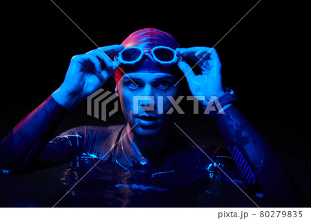 authentic triathlete swimmer having a break during hard training on night neon gel light authentic triathlete swimmer having a break during hard training on night neon gel light 80279835