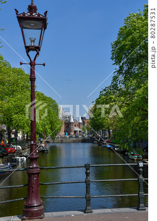 Amsterdam, the Netherlands. April 2020. Bridge over a canal with view at the Waag. 80287531