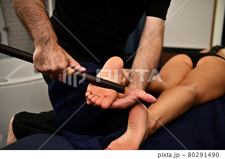 Close up of therapist hands massaging female legs with bamboo stick. Thai foot massage at the spa salon Close up of therapist hands massaging female legs with bamboo stick. Thai foot massage at the spa salon 80291490