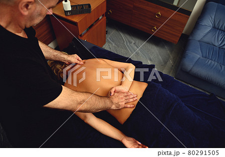 Top view of professional chiropractor, osteopath, masseur doing remedial therapeutic body massage to woman customer of spa salon in wellness center Top view of professional chiropractor, osteopath, masseur doing remedial therapeutic body massage to woman customer of spa salon in wellness center 80291505